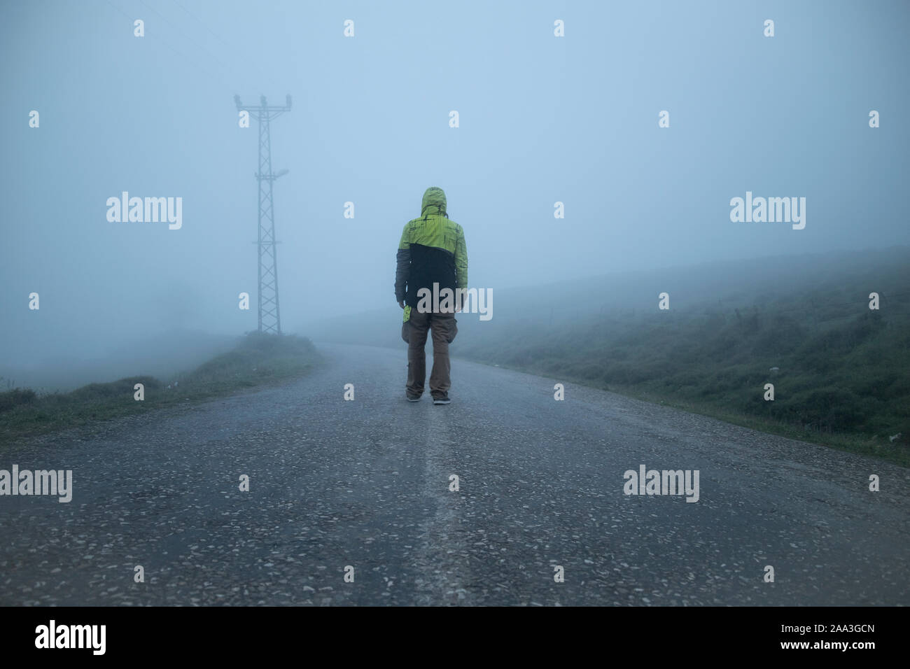 Lonely Man Walking Into The Unknown In A Foggy Road With A Yellow Jacket Stock Photo Alamy