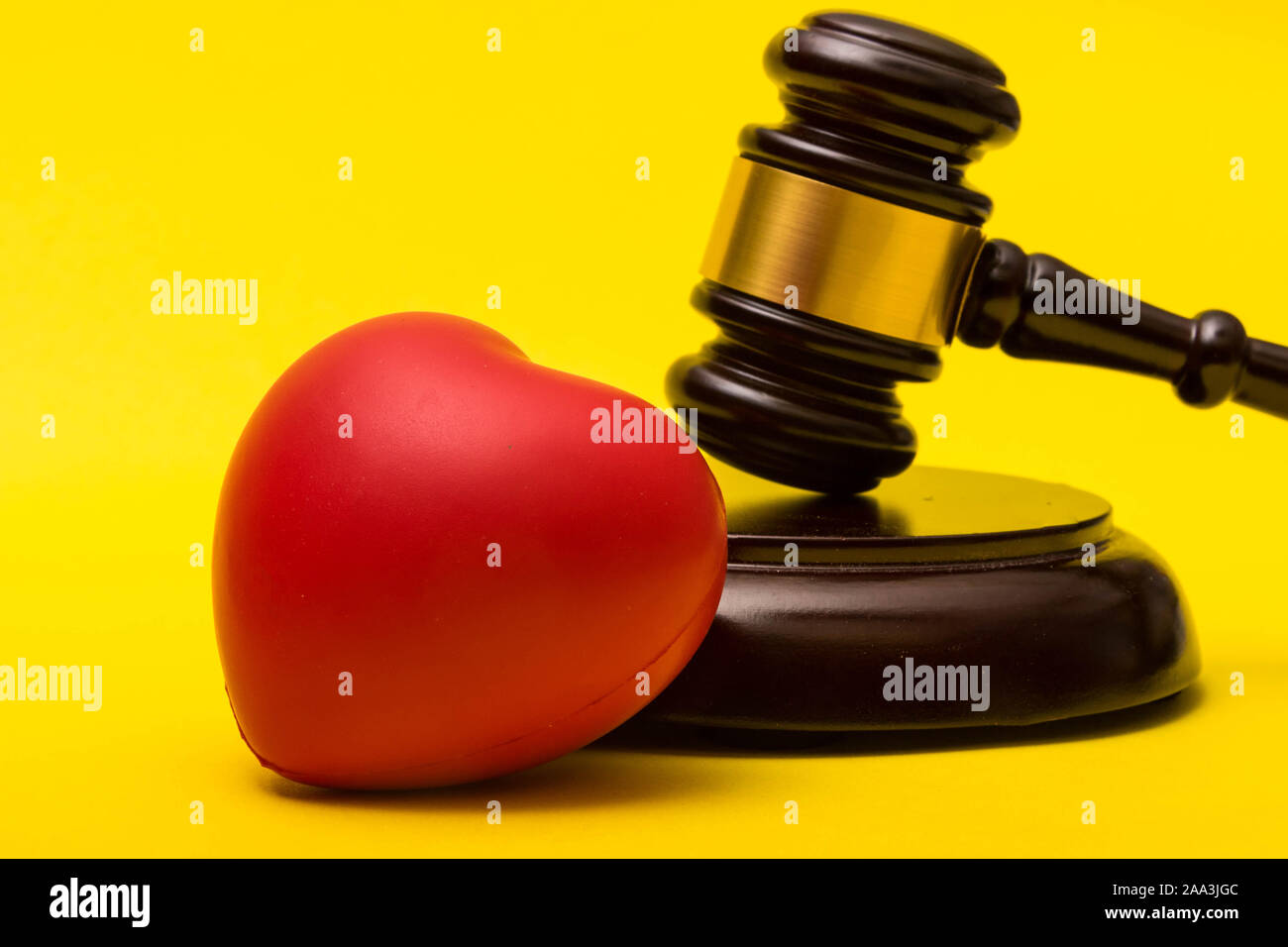 Medical malpractice lawsuit concept showing a gavel and a heart on a yellow background Stock Photo