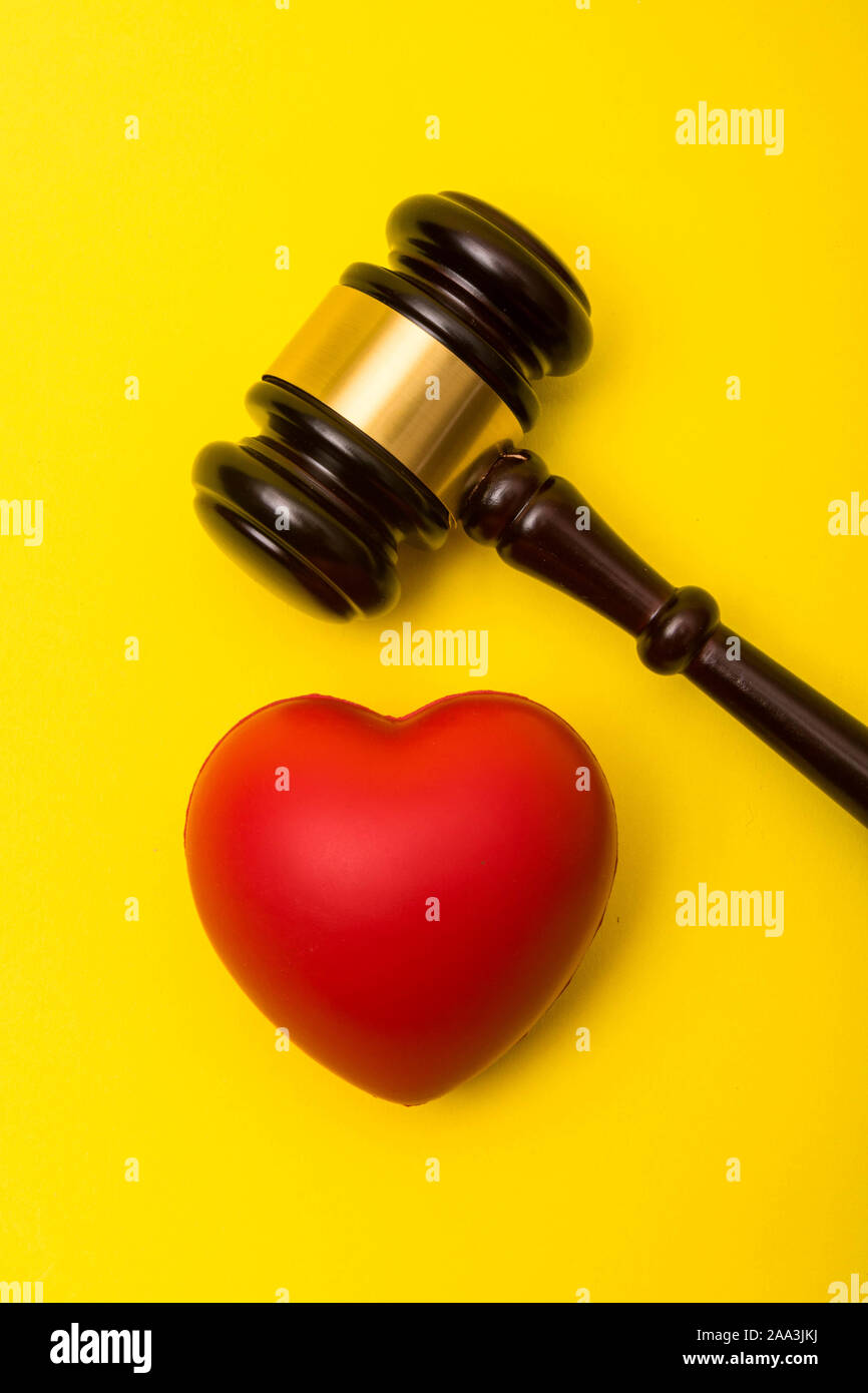 Medical malpractice lawsuit concept showing a gavel and a heart on a yellow background Stock Photo