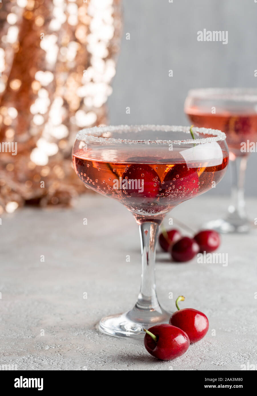Alcohol sparking drink in champagne glasses with sweet cherry in it. Concept of holiday beverages Stock Photo