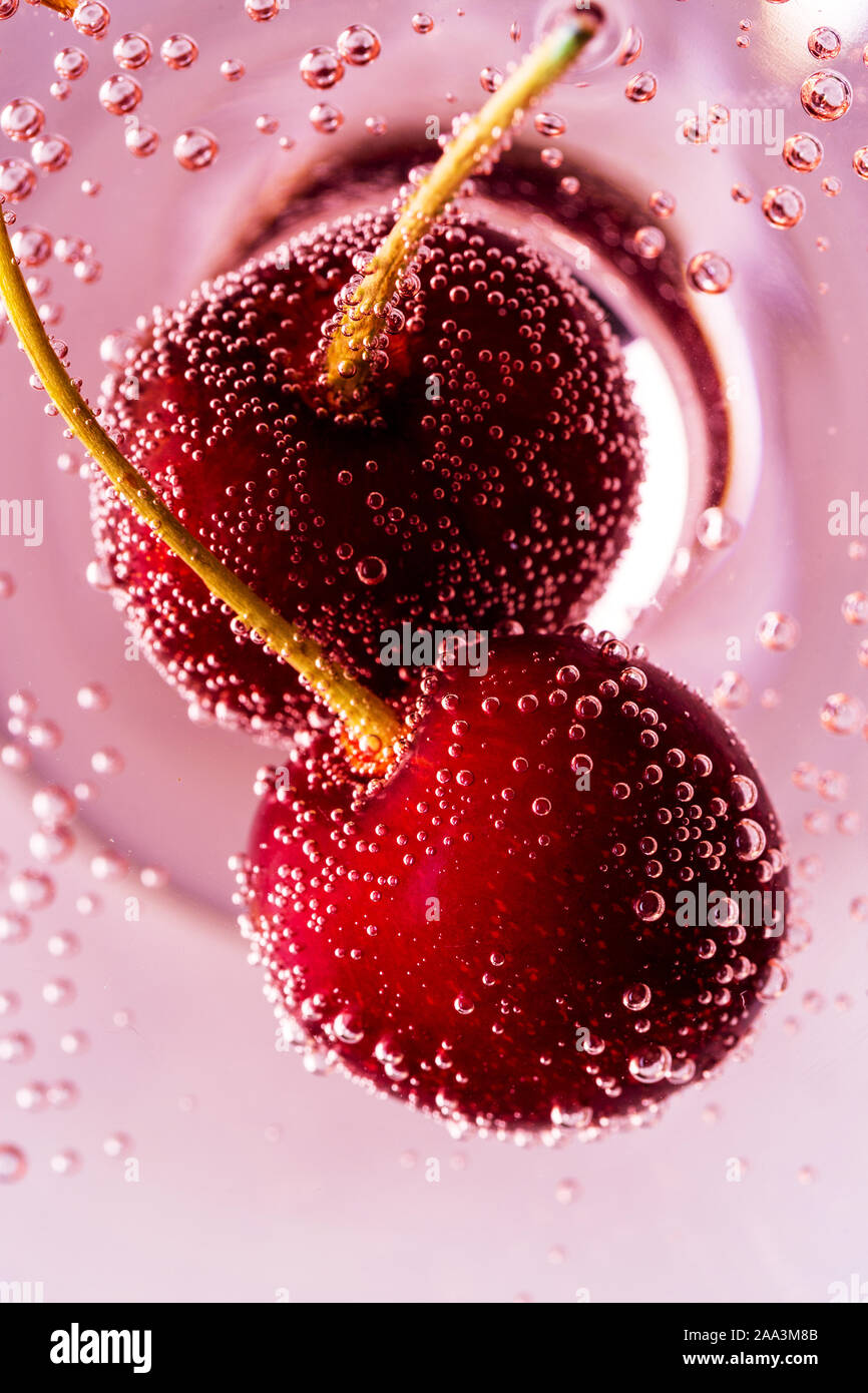 Sweet cherry in sparkle close up with pink beverage. Concept of festive drink with berries for party Stock Photo