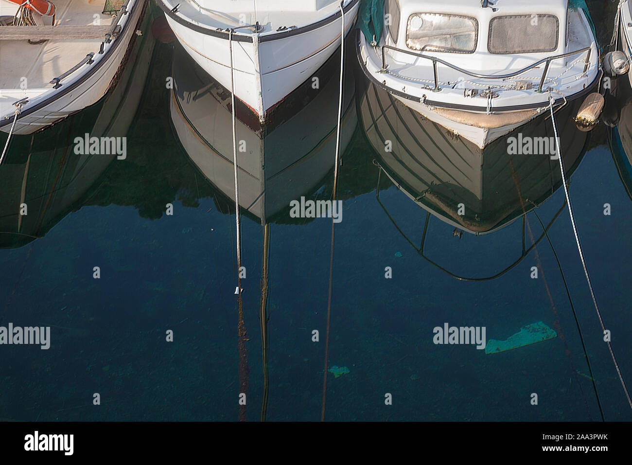 three small boats on calm water in harbour reflecting themselves Stock ...