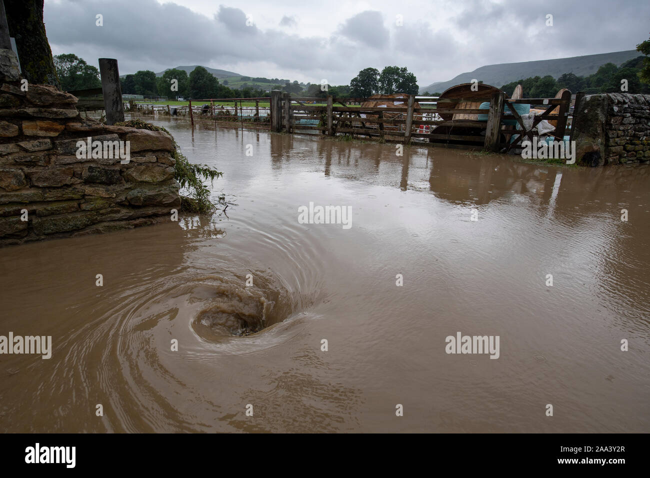 Water going down a road drain after a thunderstorm, creating a