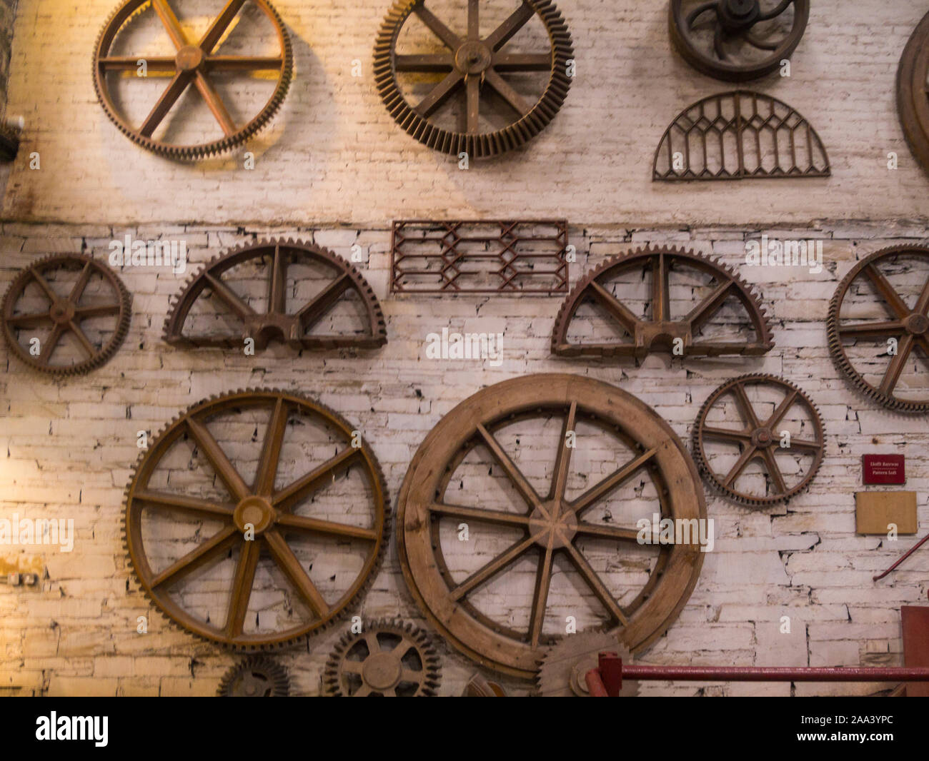 Cog wheels displayed in one of 19thc workshops of disuded Dinorwic quarry National Slate Museum Llanberis Gwynedd North Wales UK where visitors can le Stock Photo