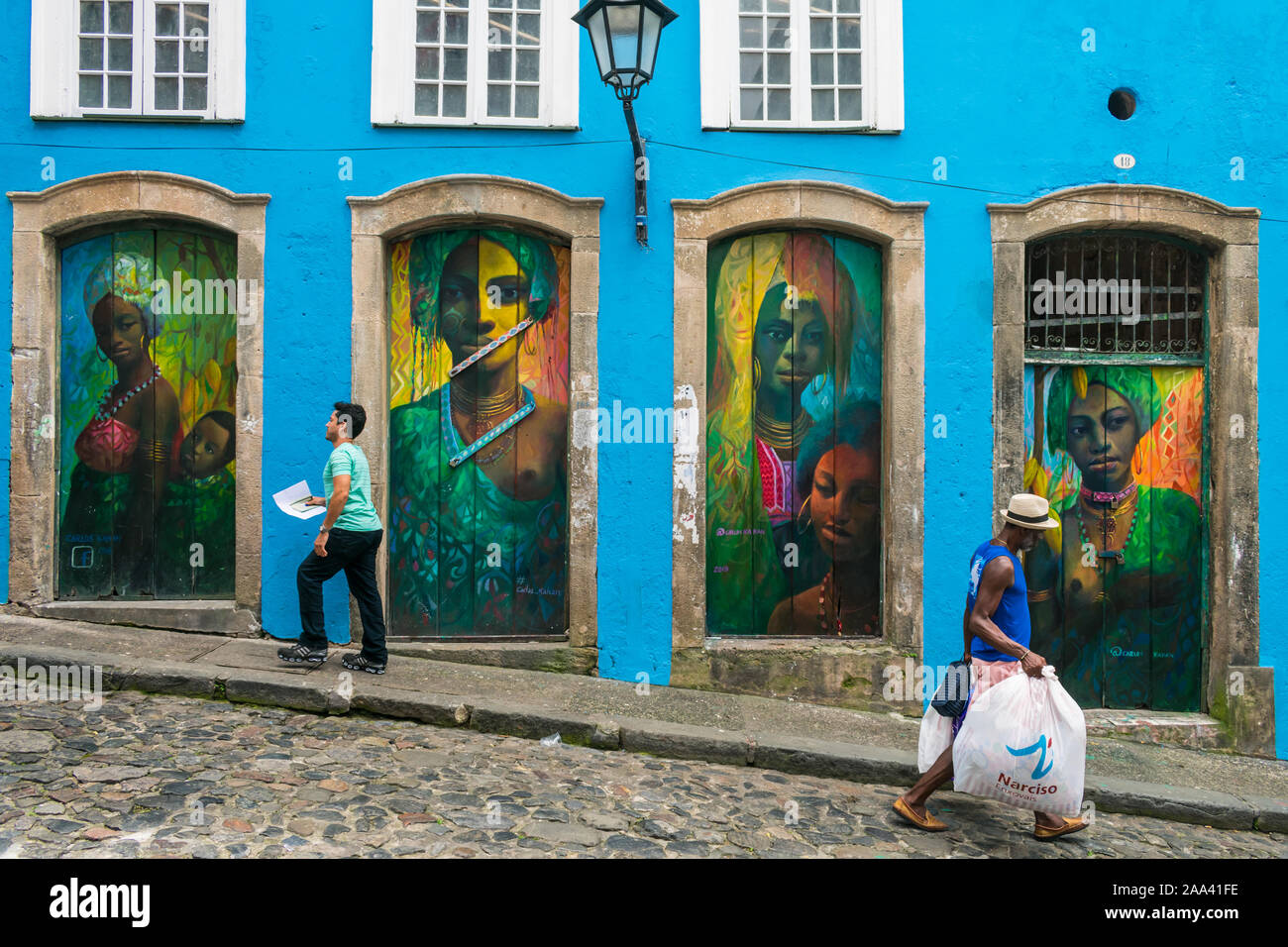 Locals passing in front of beautiful art murals with African women ...