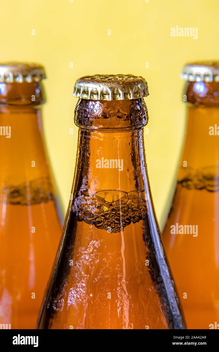 A chilled bottles with drink on yellow background. Beer in a dewy glass