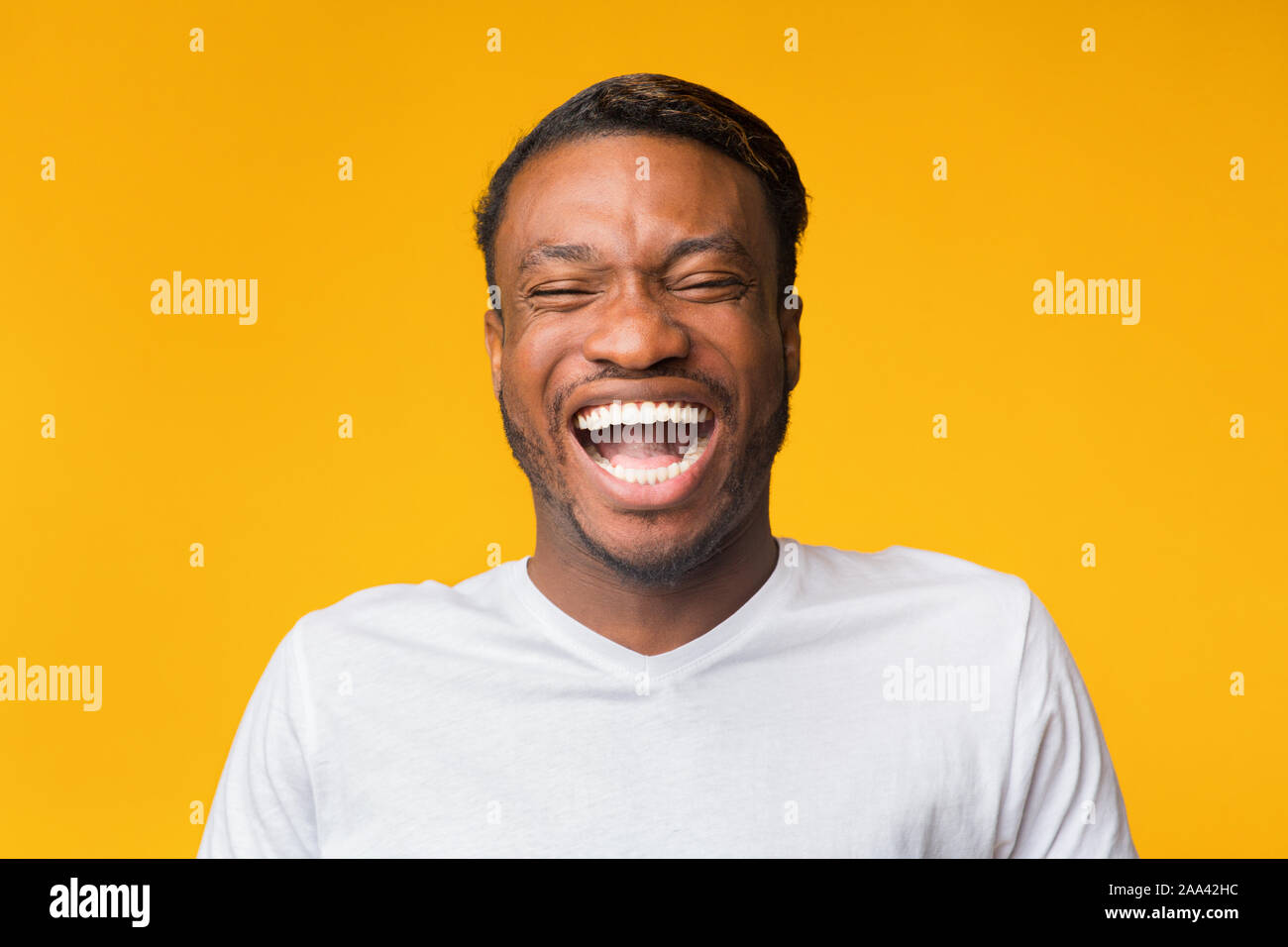 Portrait Of Laughing Black Man Standing Over Yellow Background, Studio Stock Photo