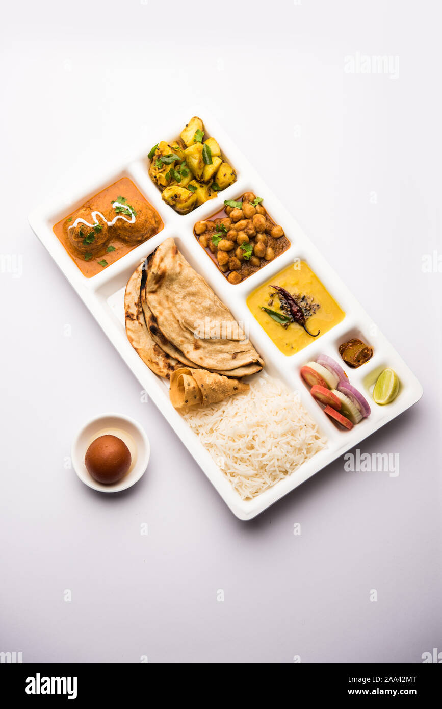 Indian vegetarian Food Thali or Parcel food-tray with compartments in which Malai Kofta, chole, Dal tarka, dry aloo sabji, chapati and rice with sweet Stock Photo