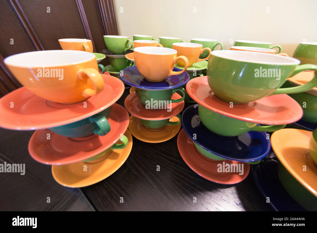 Brightly coloured cups and saucers, stacked in piles ready for use