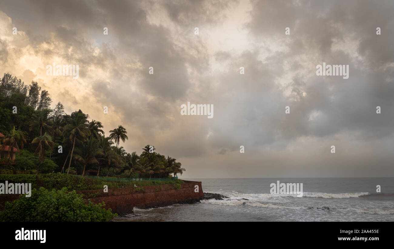 Landscape of the seashores of Goa with sky, clouds and palm trees during monsoon  Stock Photo