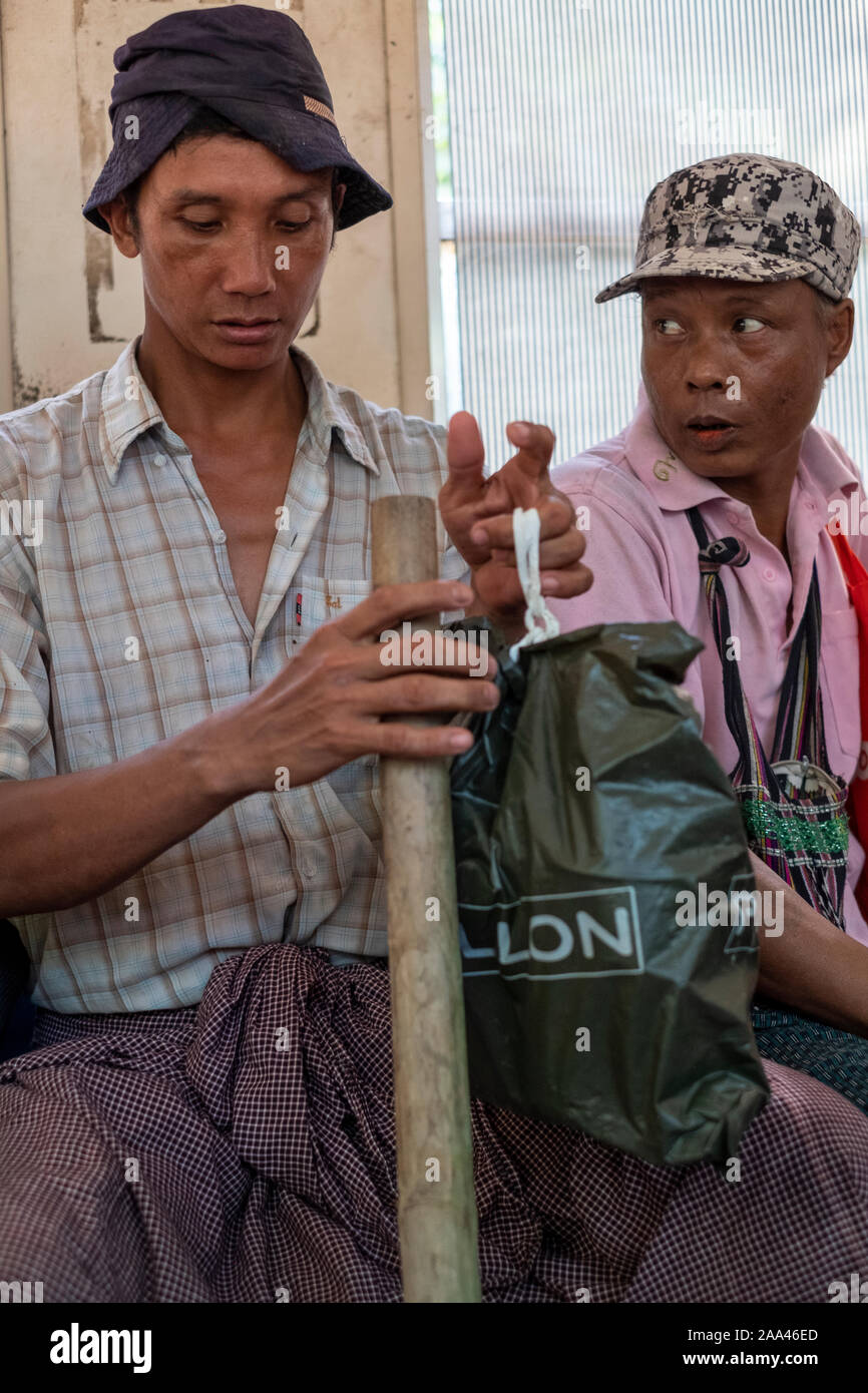 Passengers on the circular local train of Yangon, Myanmar (Burma) including these two construction laborers with their hats and tools Stock Photo