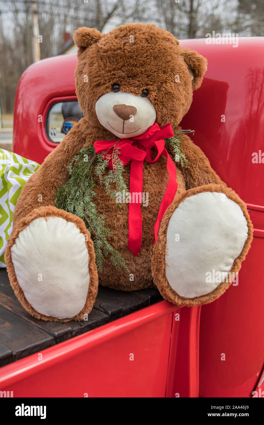 A big Teddy Bear on the back of an old red pick-up truck Stock Photo