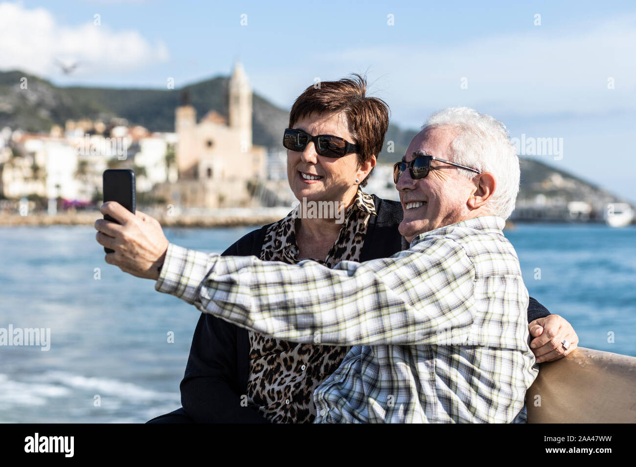 Two seniors using a mobile in Sitges, Spain Stock Photo