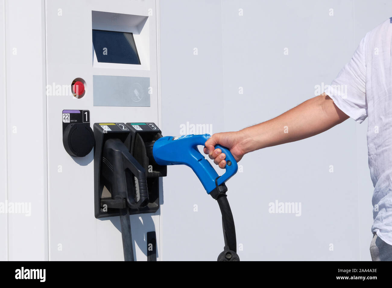 Eco friendly transport concept. Hand of driver is holding charger for electric cars. Electric charging station. Stock Photo