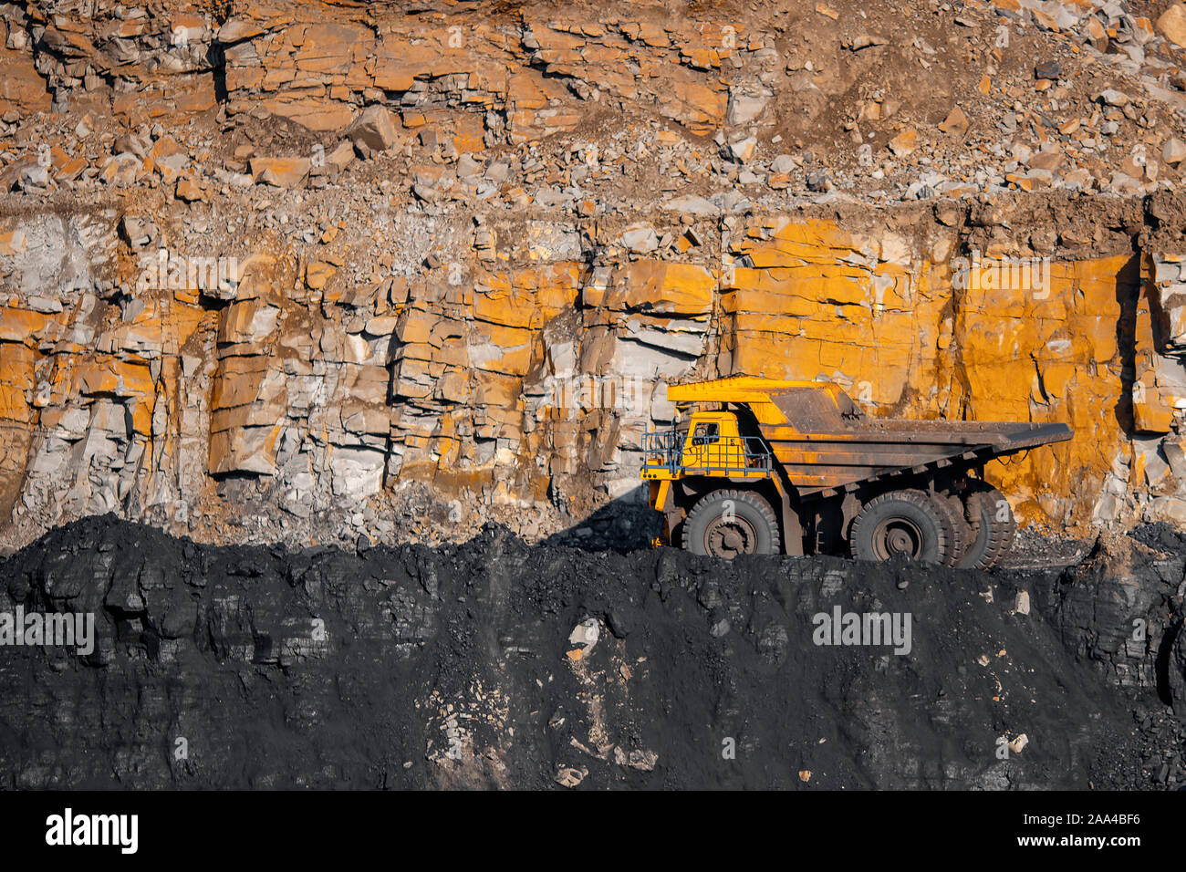 Big yellow mining truck laden anthracite moves open pit coal mine. Stock Photo