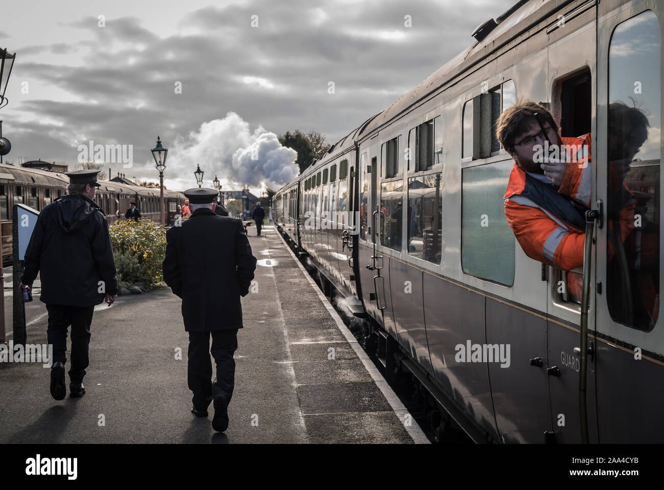 Rear view of staff walking along platform at Kidderminster vintage train station, early morning departure time Severn Valley heritage steam railway UK. Stock Photo