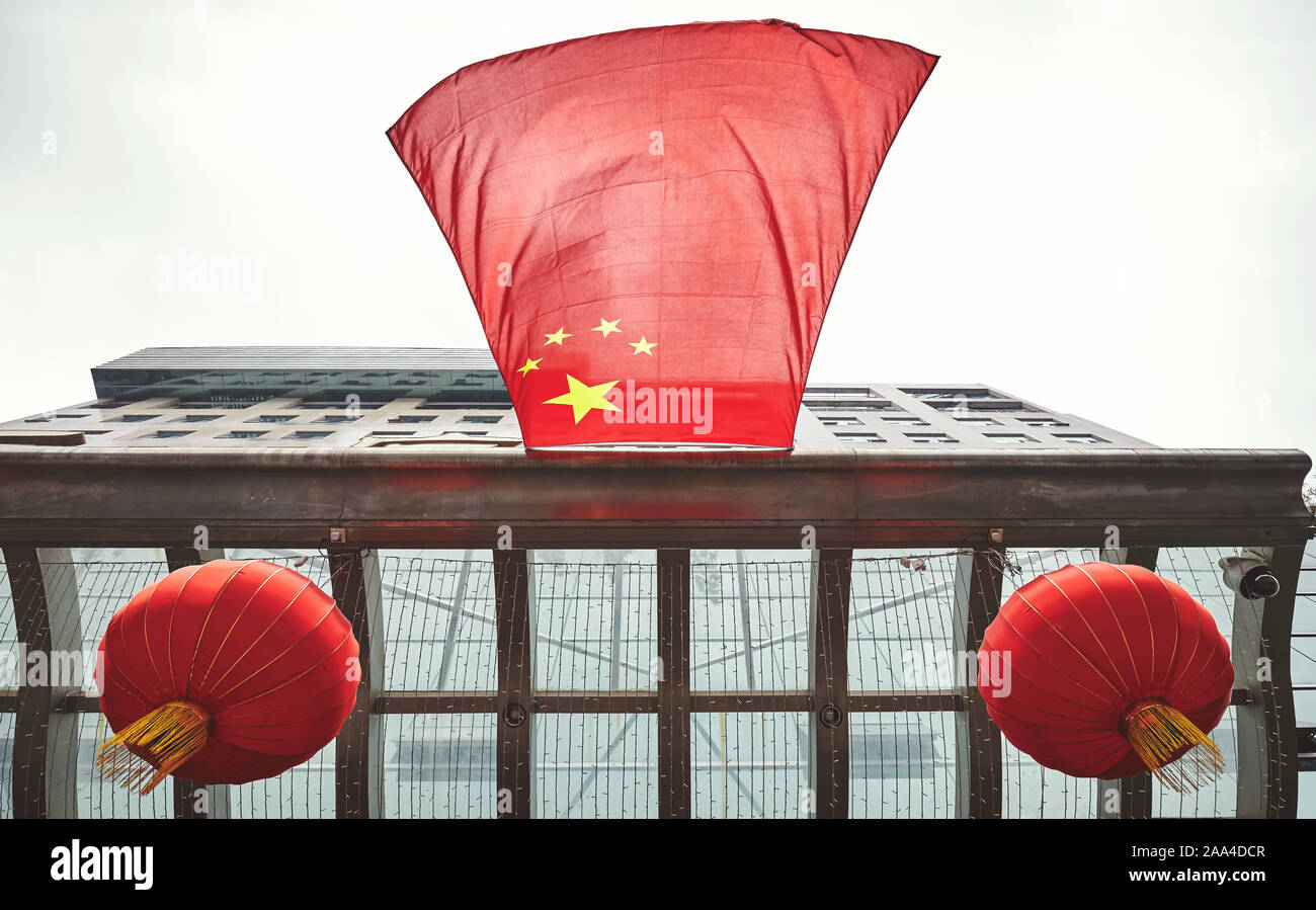 Looking up at Chinese flag and red lanterns on a building. Stock Photo