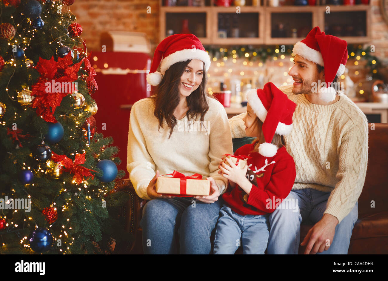 Mother and daughter exchanging xmas gifts next to Christmas tree Stock Photo
