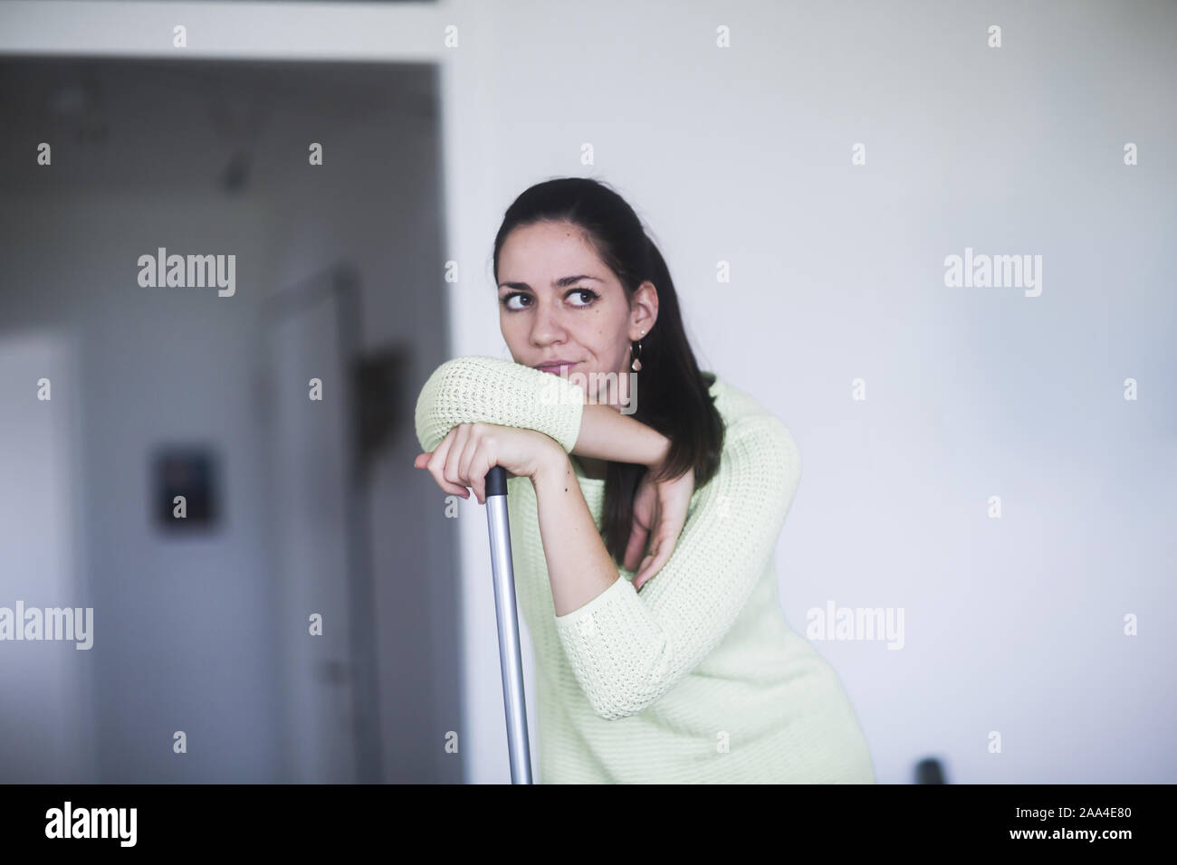 Frustrated woman leaning on a broom Stock Photo