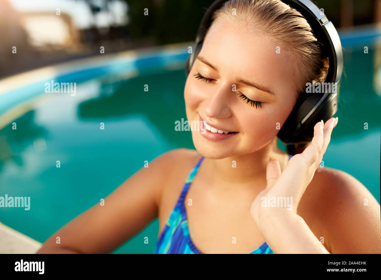 Relaxed smiling woman listening to music in headphones bathing in