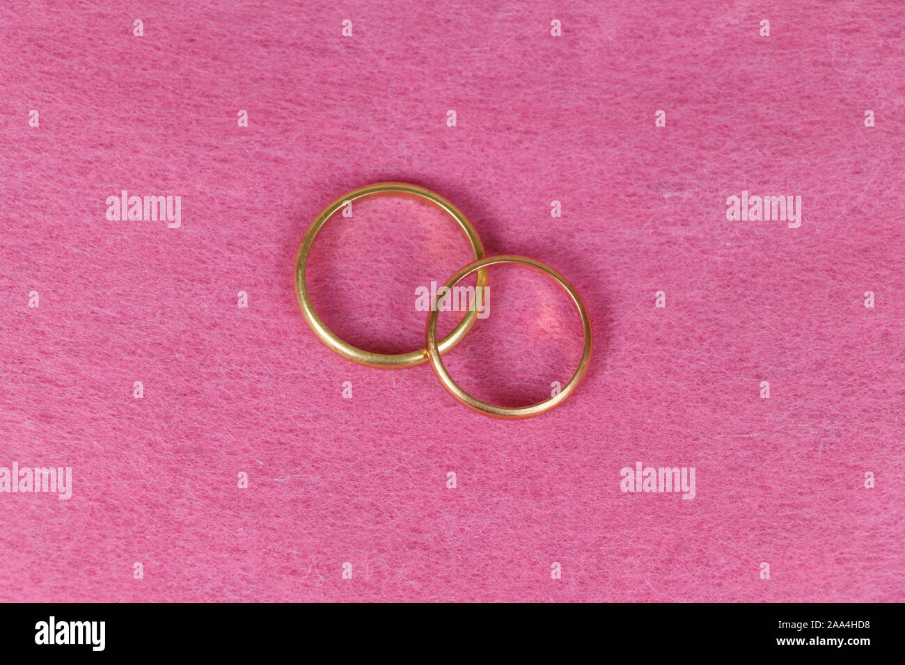 Two wedding rings in gold on pink background Stock Photo