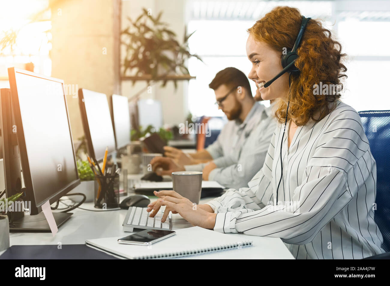 Positive woman operator consulting client by phone Stock Photo