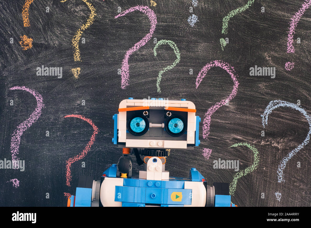 Tambov, Russian Federation - November 15, 2019 Lego Boost Vernie the Robot standing against blackboard with colorful question marks. Stock Photo