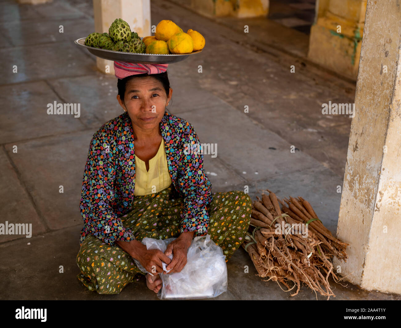 Burmese woman selling custard apples and oranges which she balances on a tray on her head in a temple of Bagan, Myanmar (Burma) Stock Photo
