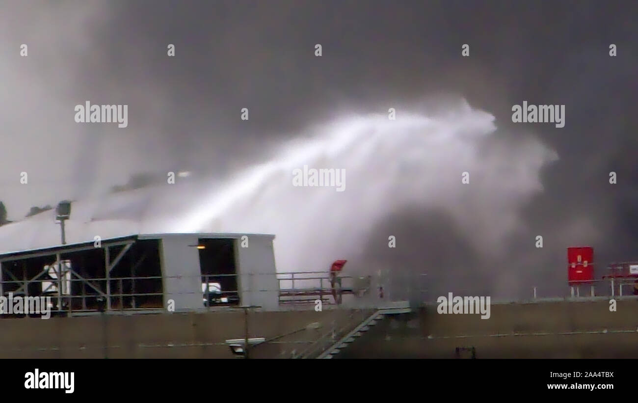Firefighter water jet extinguish the fire started near a petrol storage tank. Huge fire blaze