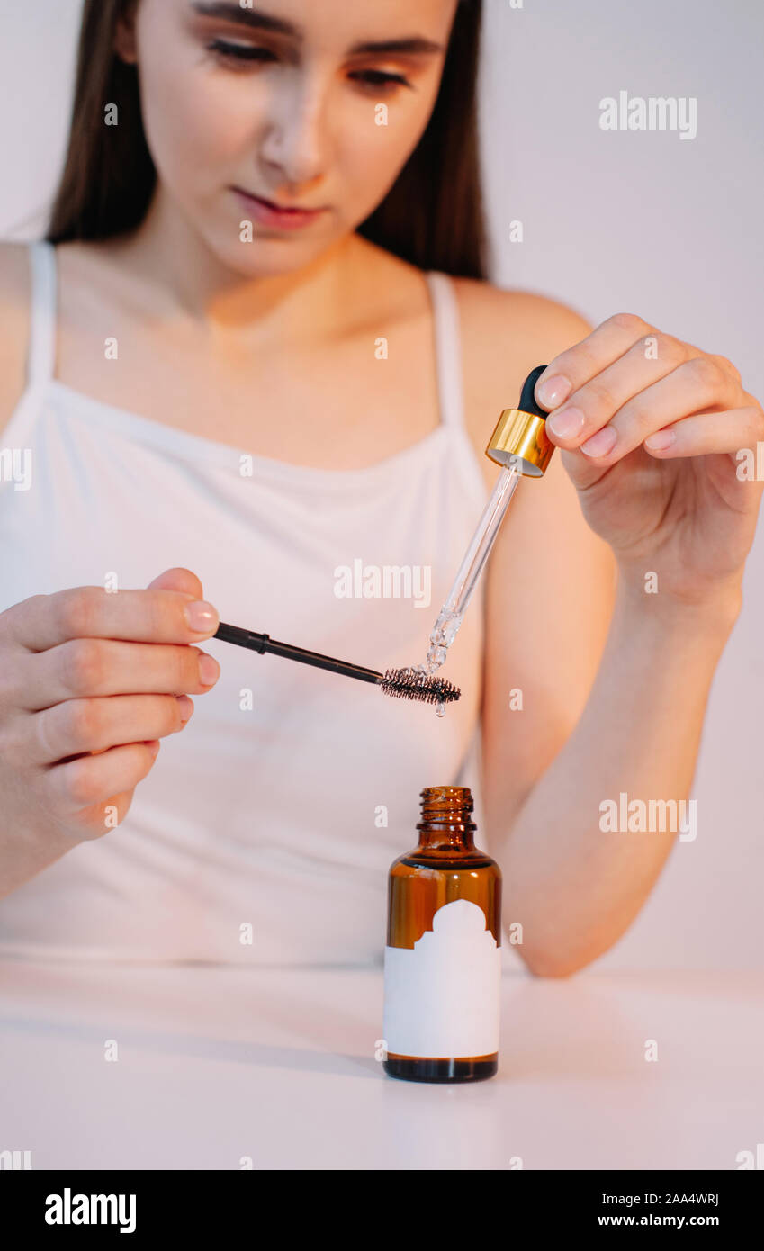 Woman applying oil to an eyelash brush Stock Photo