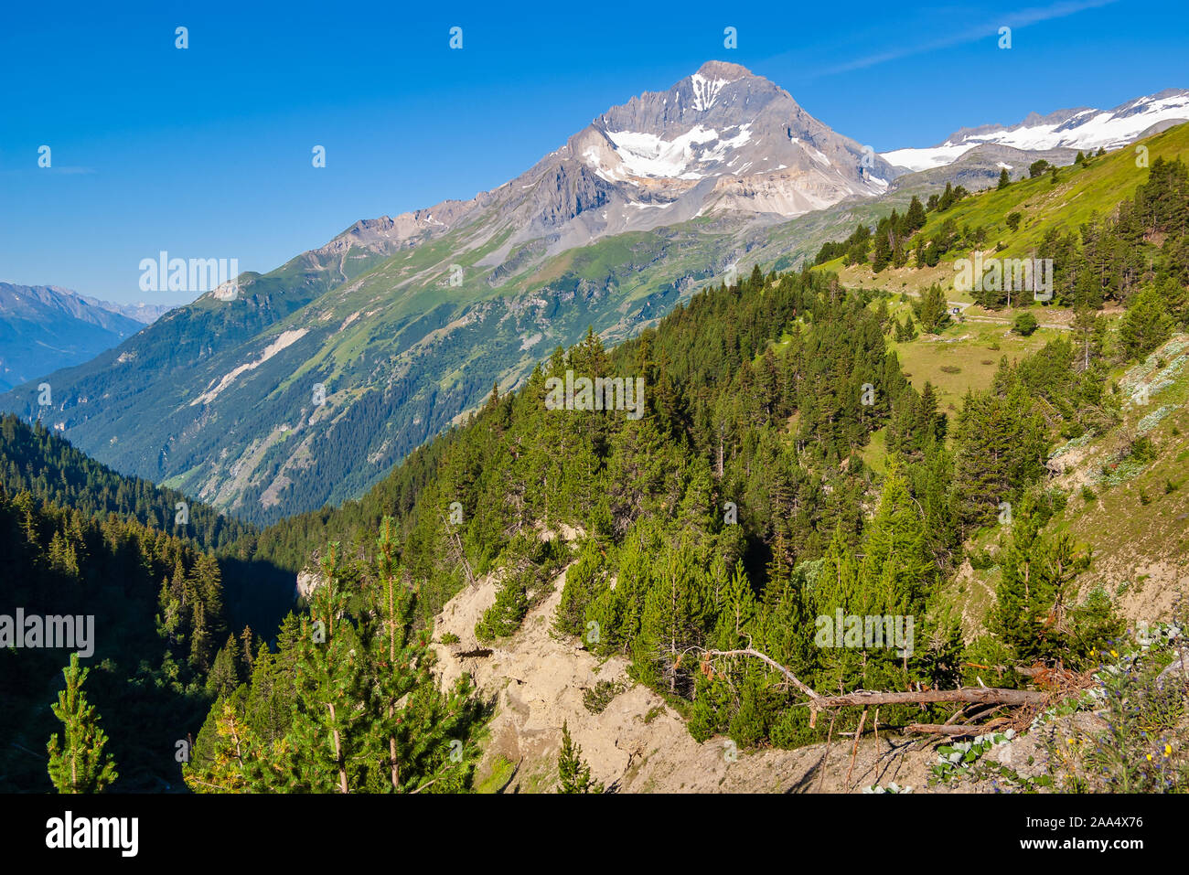 Summer landscape from the French Alps. Peak with steep slopes and winding high mountain road on them. Stock Photo