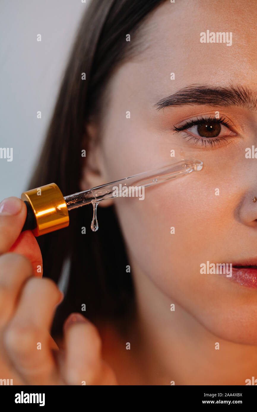 Close-up of a Woman applying serum to her face Stock Photo