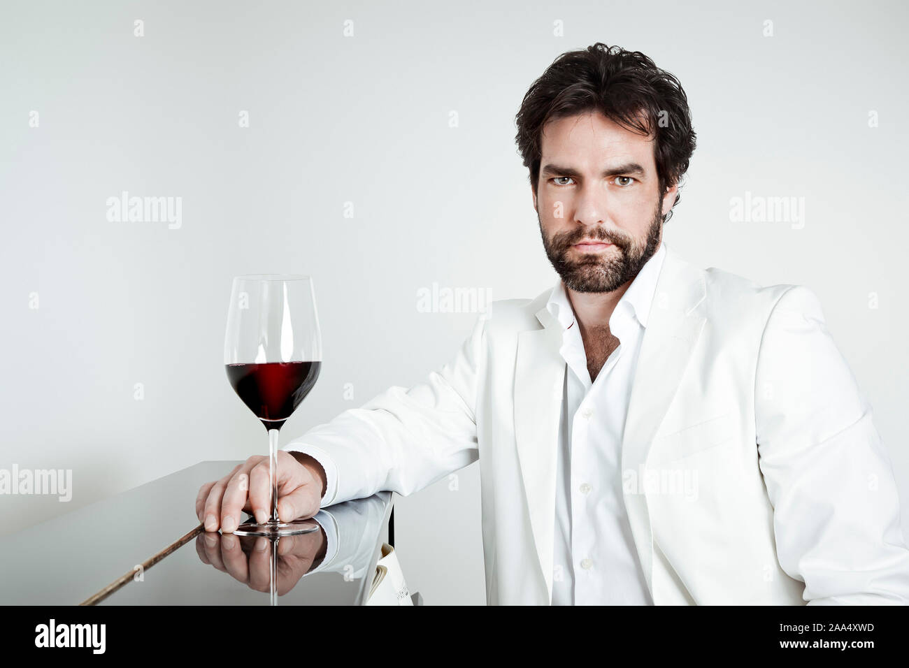 Ein edel gekleideter Mann mit einem Glas Wein in der Hand Stock Photo