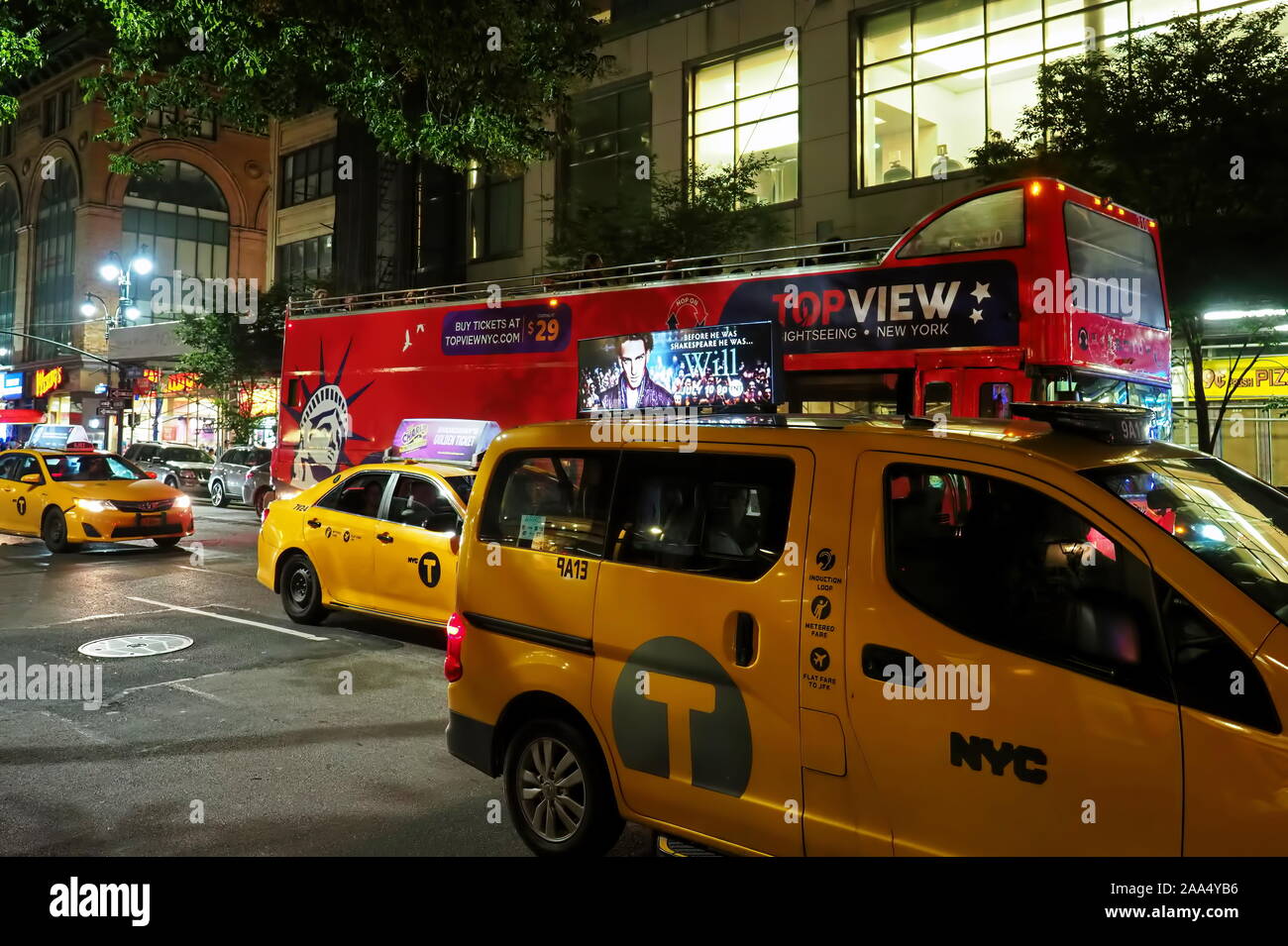 New York City, NY USA. Jul 2017. Yellow cabs and double deck tourist bus at a Manhattan night. Stock Photo
