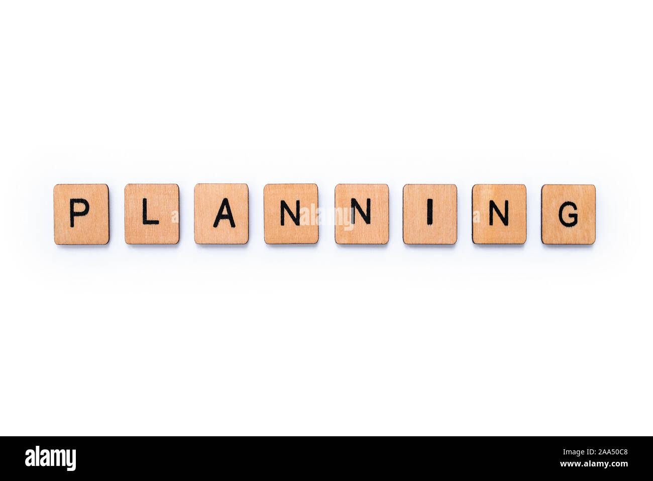 The word PLANNING, spelt with wooden letter tiles over a white ...