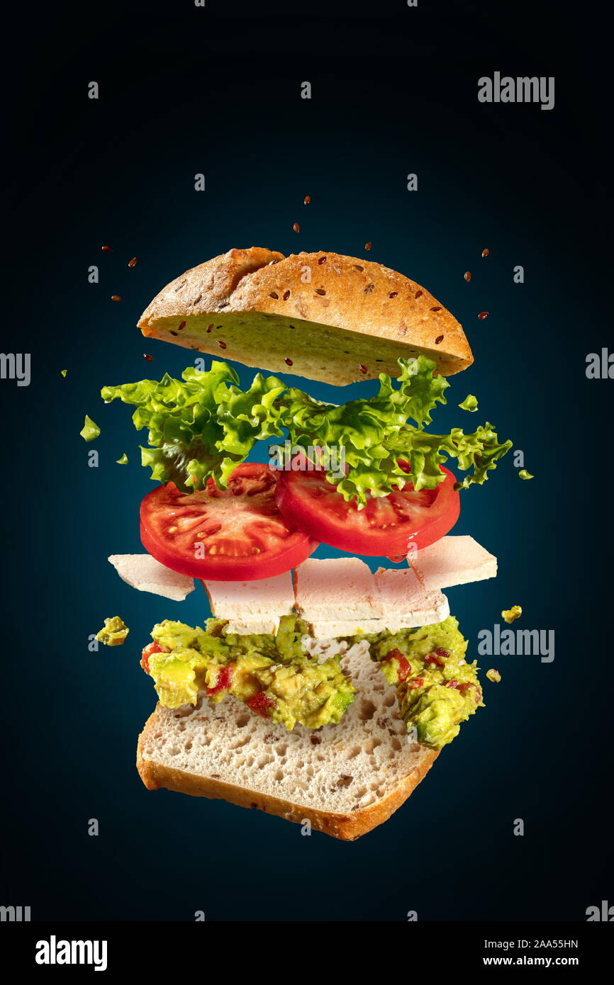 Exploded and flying vegetarian sandwich with guacamole and tofu cheese on blue Stock Photo
