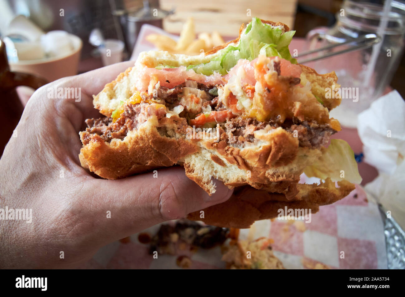 man eating larger burger and fries in a local american diner in florida usa Stock Photo