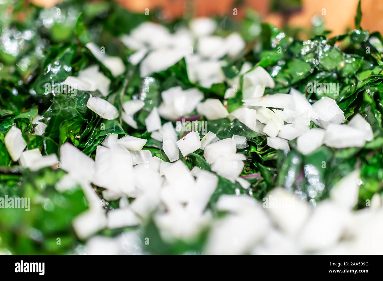 Macro closeup of healthy chopped green kale massaged vegetable salad showing texture with sweet white onions vegan meal Stock Photo