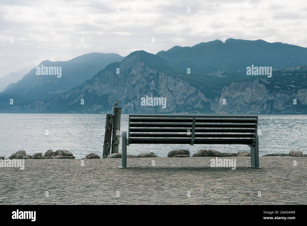 Bench by Lake Garda facing villages on the mountain Stock Photo