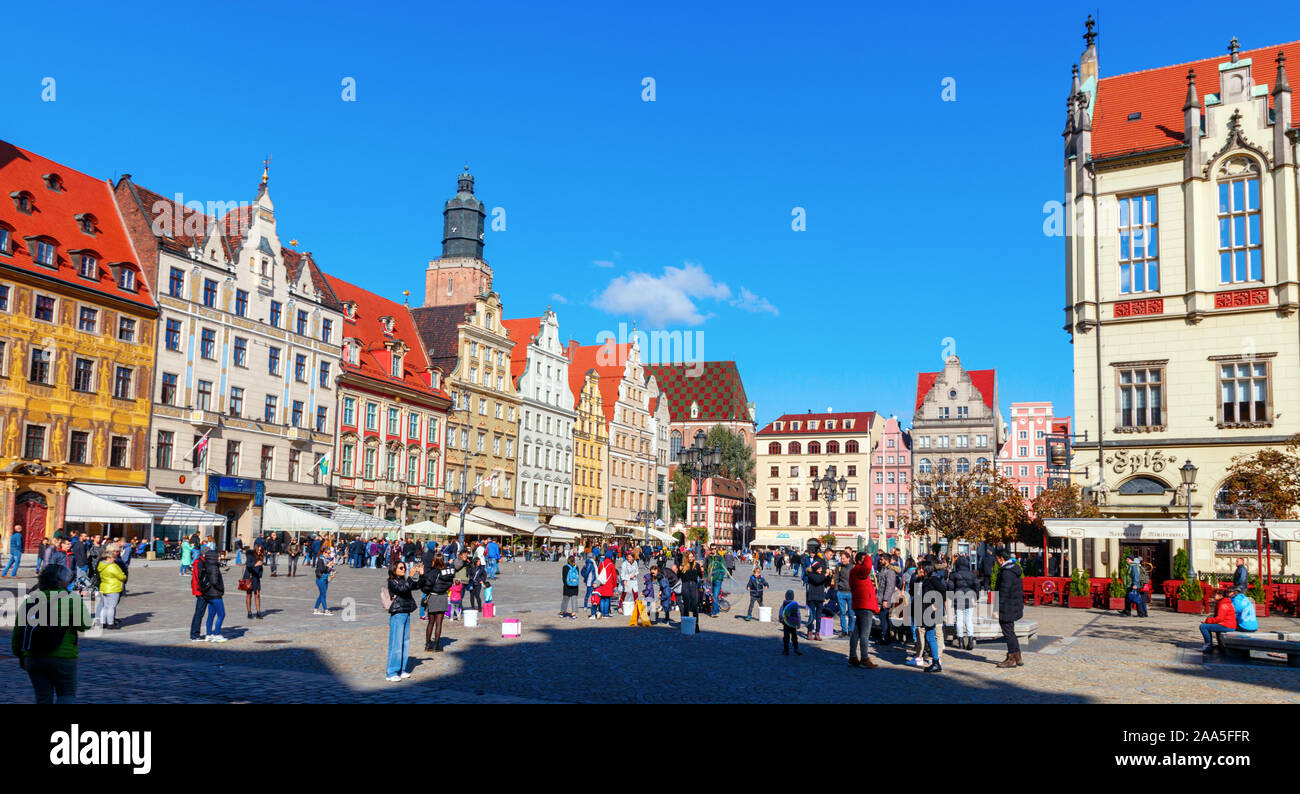 Sightseeing tourists at the medieval Wroclaw Market Square with its colorful houses and the St Elizabeth's church bell tower in the background. Poland Stock Photo