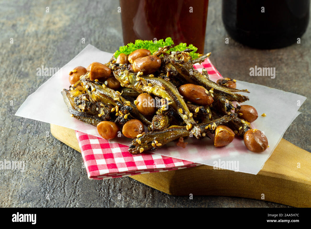 Tazukuri, candied sardines served with red beer. Dried sardines lightly coated with honey, roasted sesame and peanuts. Stock Photo