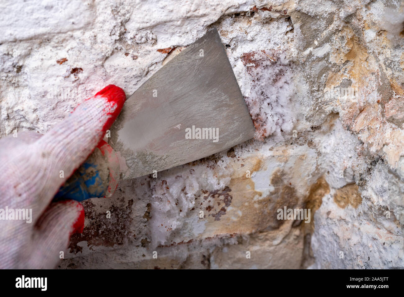 Removing mildew from the brick wall with a metal spatula. Small