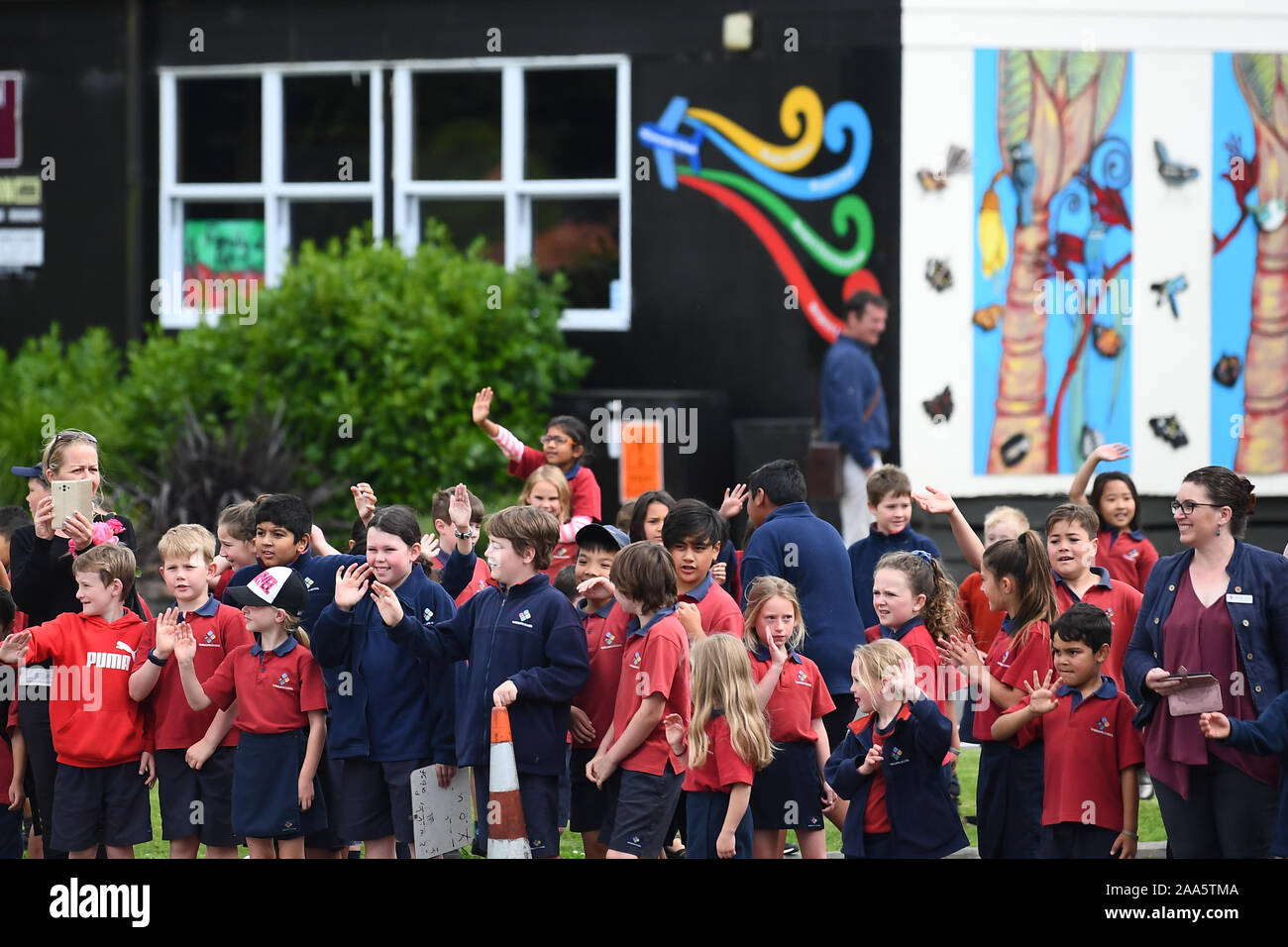 School children wave as the convoy carrying the Prince of Wales and the Duchess of Cornwall arrives at Waitangi Treaty Grounds, the Bay of Islands, on the fourth day of the royal visit to New Zealand. Stock Photo