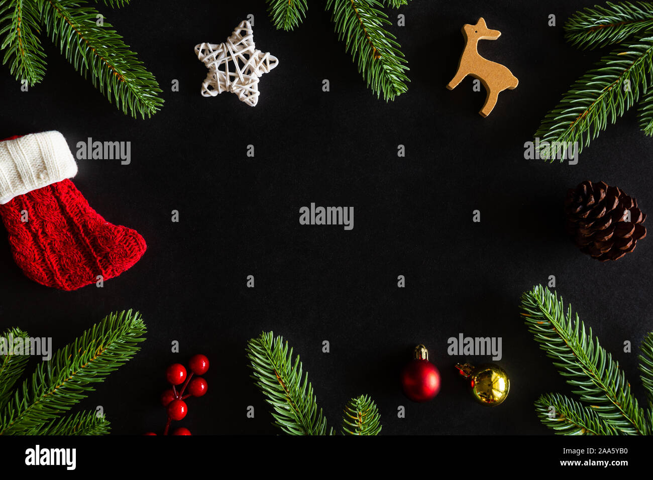 Holiday Christmas card background with festive decoration ball, stars, snowflakes, gift box, pine cones on a black background from Flat lay, top view. Stock Photo