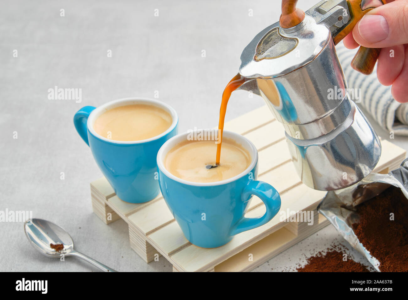 Coffee pouring in blue cups from Italian coffee espresso maker. Two coffee mugs and moka coffee pot. Stock Photo