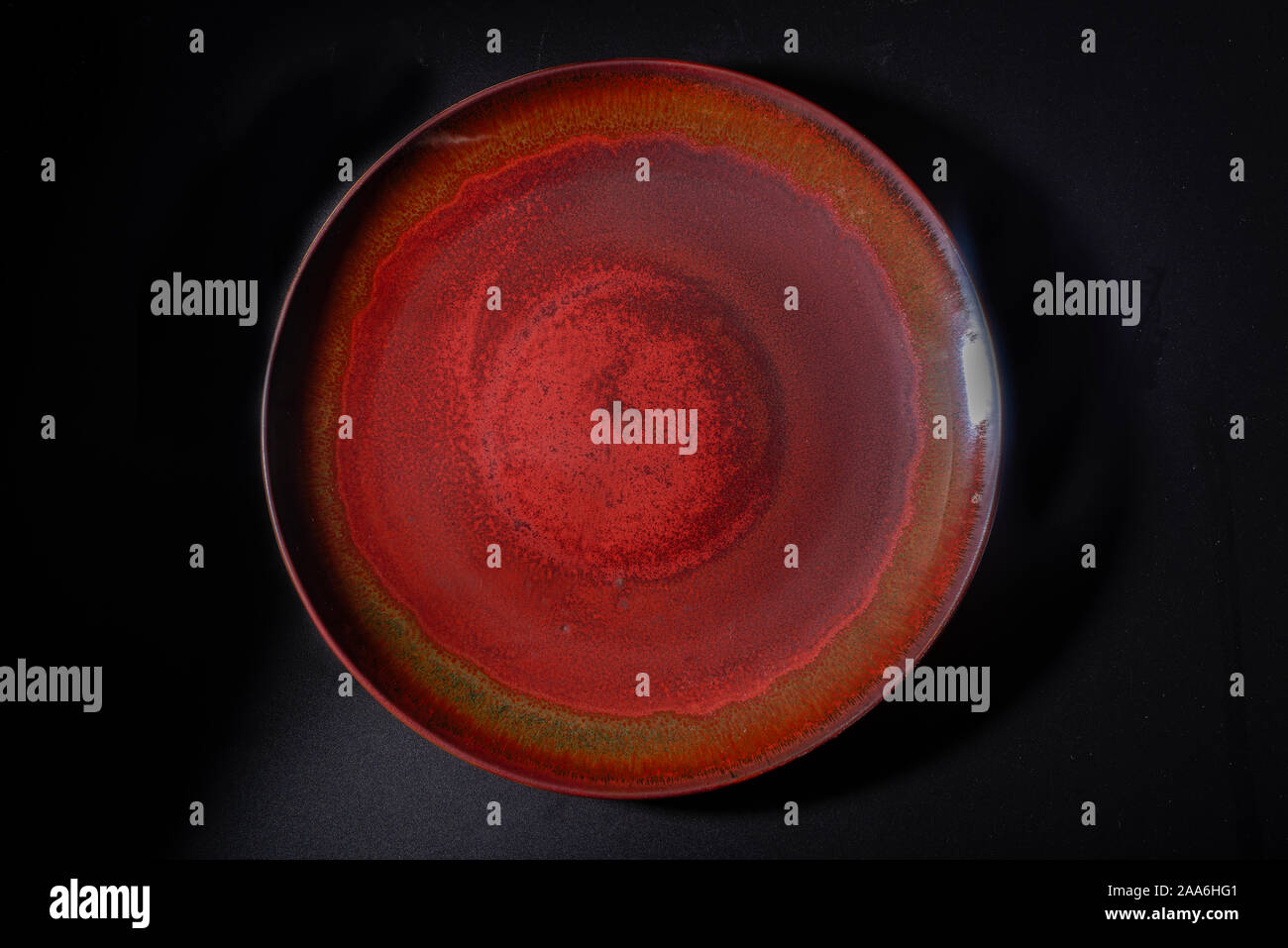 A dark red ceramic plate with a brown vintage pattern Stock Photo