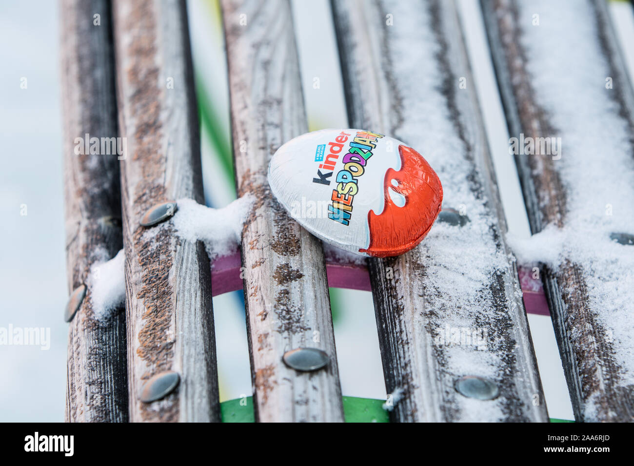 Kinder Surprise egg consists of a chocolate shell, plastic capsule with toy, and external foil wrap. Word Surprise written in Polish. made by Ferrero Stock Photo