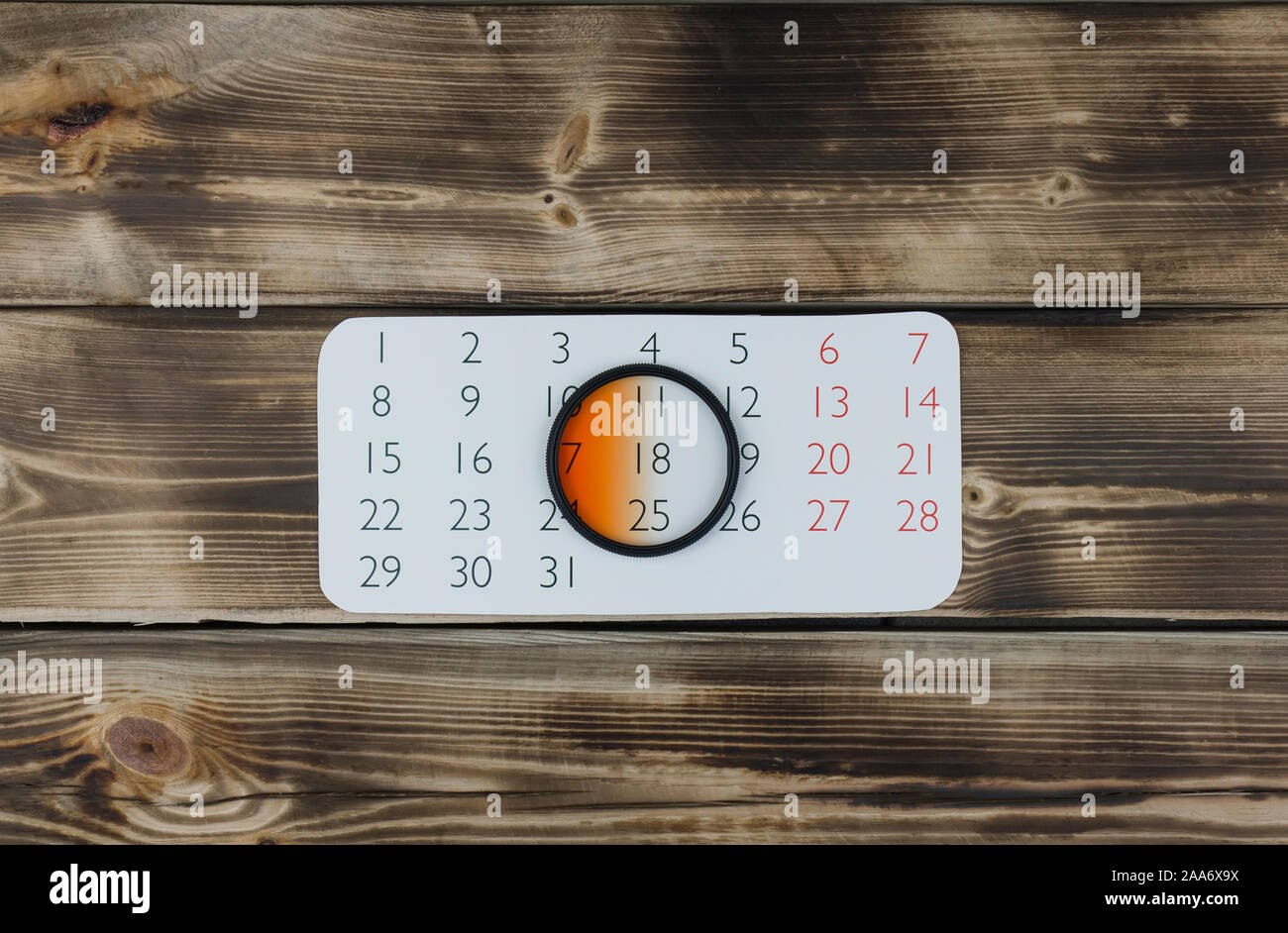 Calendar sheet and camera lens filter on wooden Stock Photo - Alamy