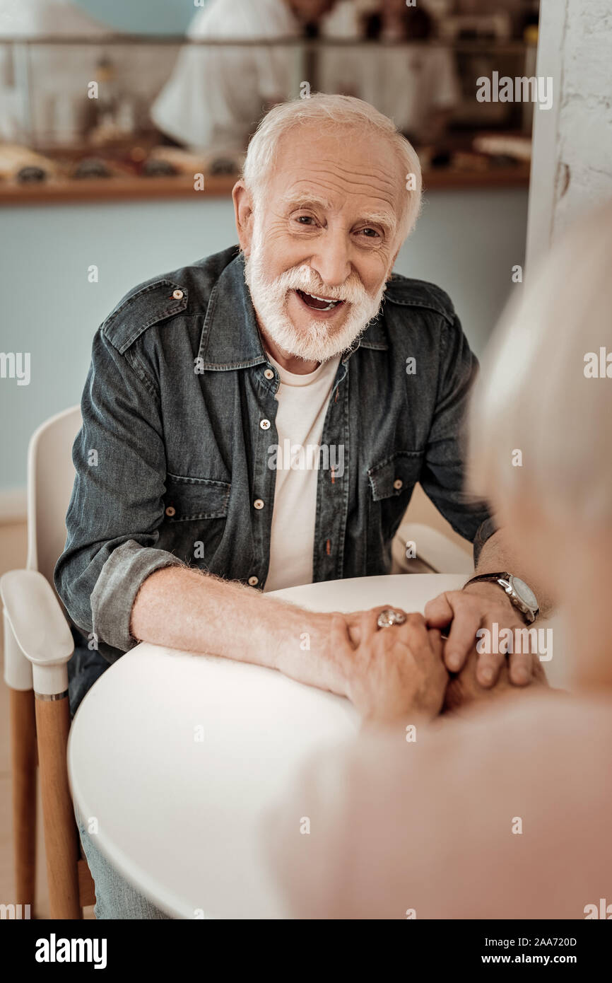 Positive elderly man smiling while looking at his wife Stock Photo