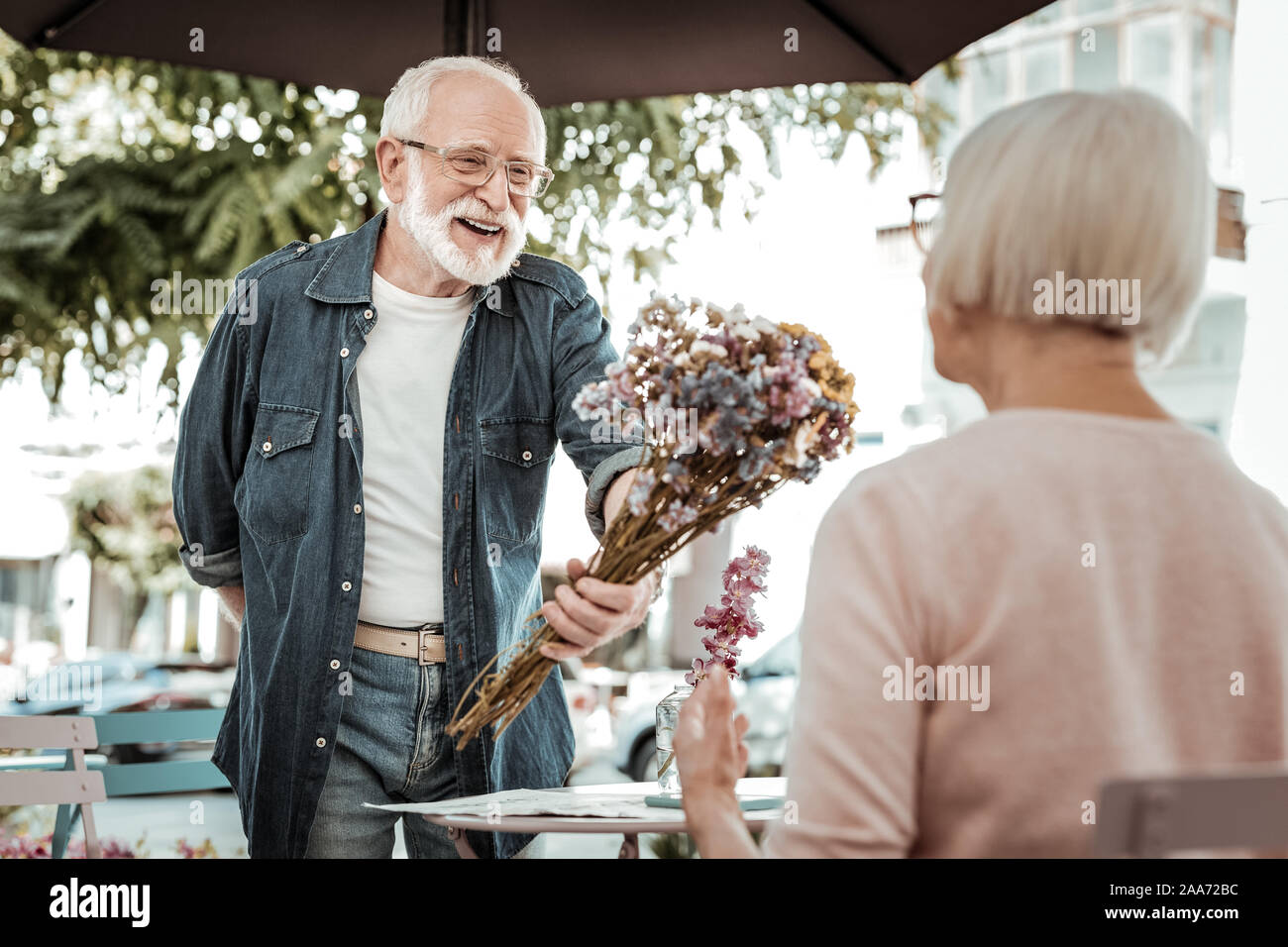 Joyful delighted man giving flowers to an elderly woman Stock Photo